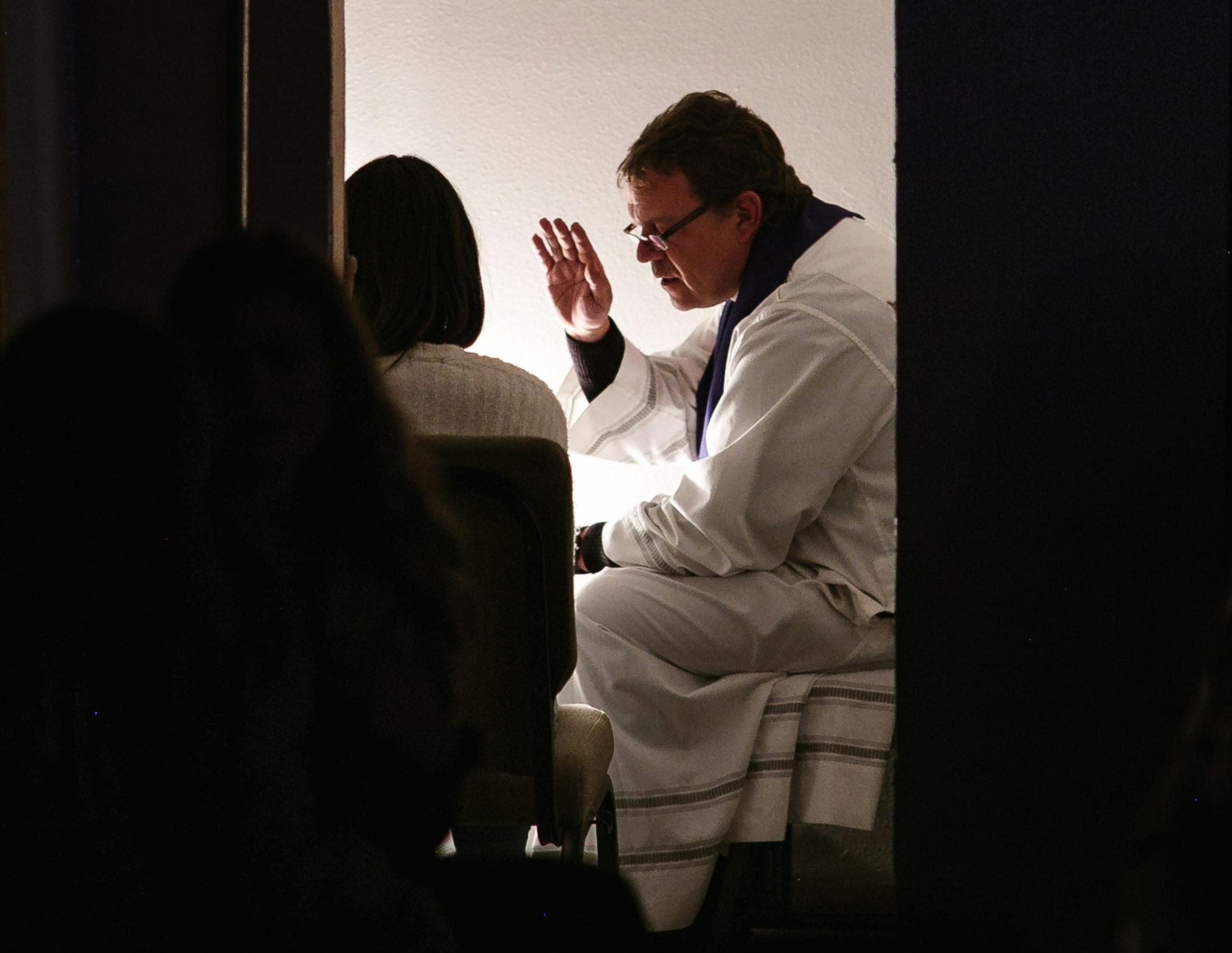 Der Pfarrer hört die Beichte des Menschen zu.